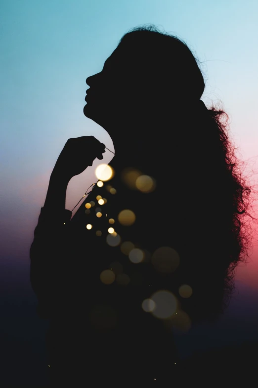 the silhouette of a woman blowing bubbles from her hair