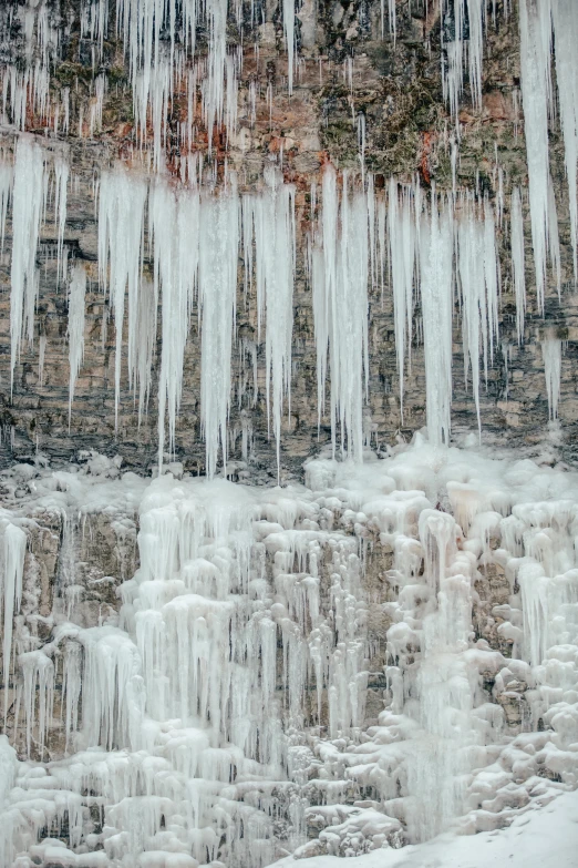 icicles are hanging over a stone wall with ice on it