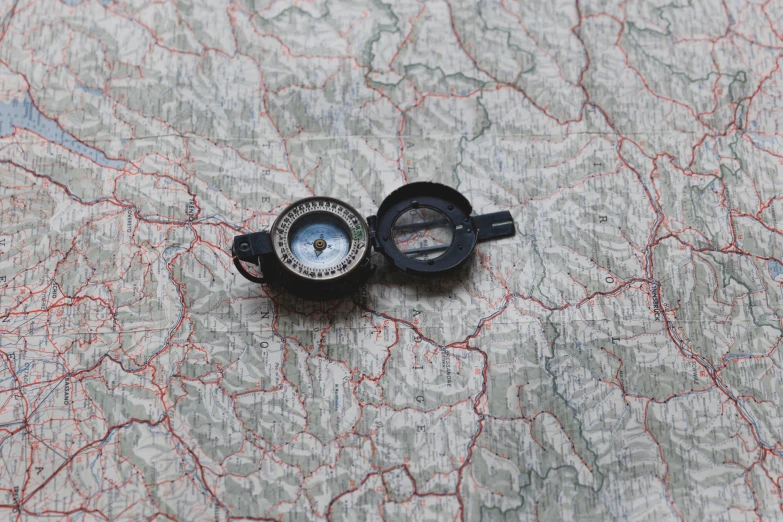 a small compass is on a map, with another map in the background