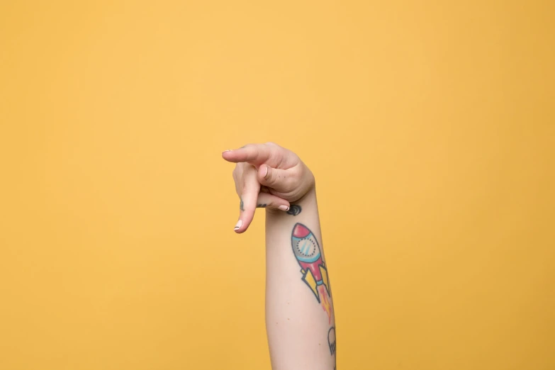 a woman's hand pointing towards a yellow background