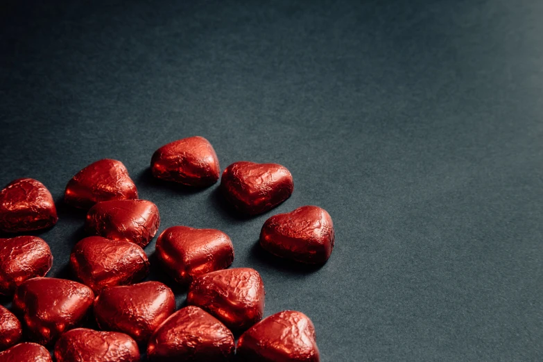 two rows of heart shaped chocolates on a dark table