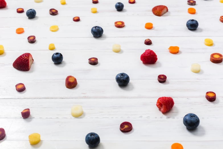 various berries are scattered next to a wooden surface