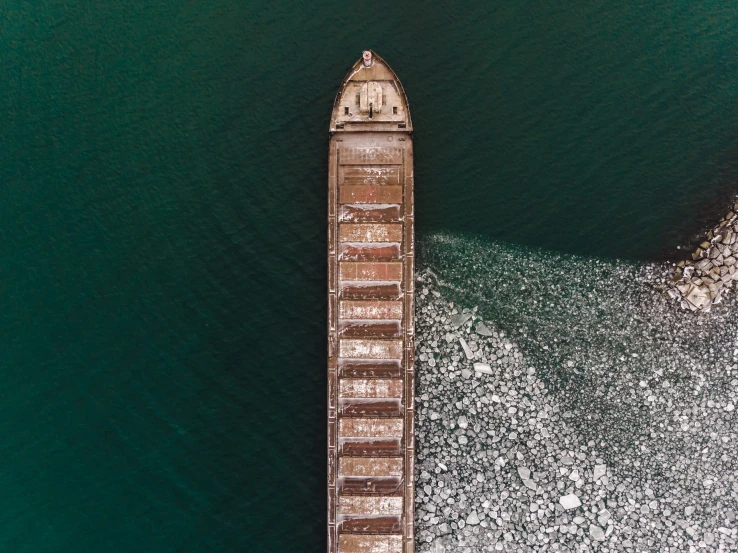 the tall ship is surrounded by small rocks and seaweed