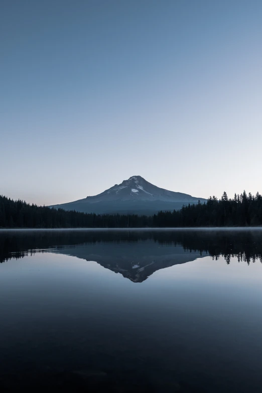 a large lake surrounded by a mountain next to a forest