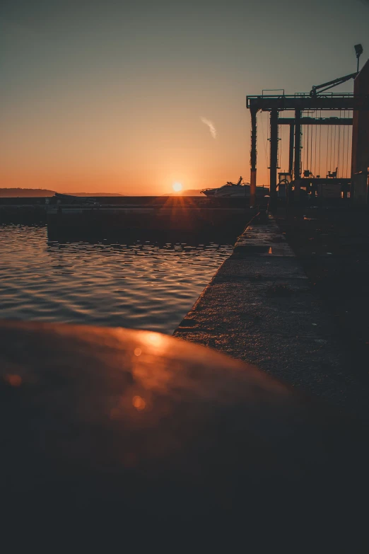 the sun is setting behind the boat dock