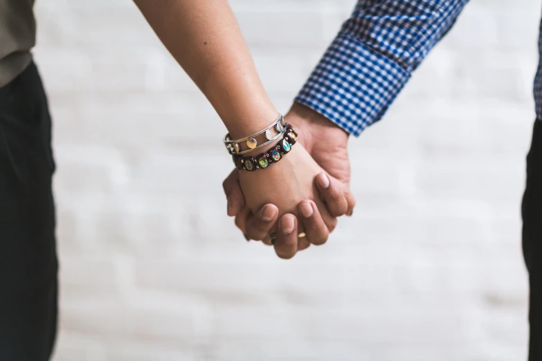 a close up of two people holding hands