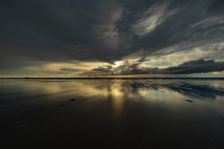 the sun sets over the horizon of a beach