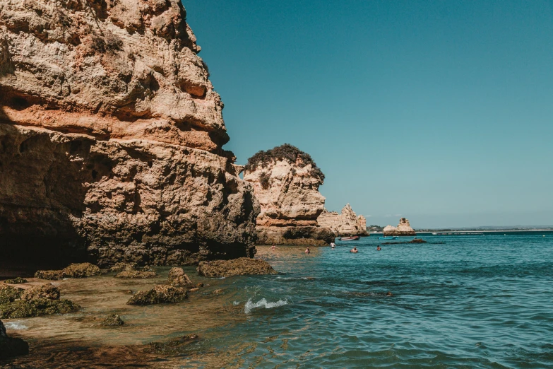 a person walking into the ocean near some rocks