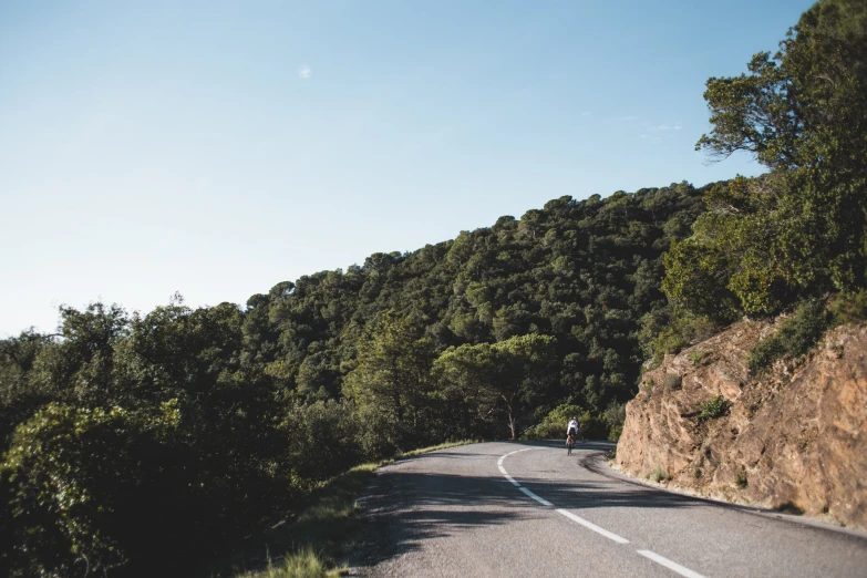 man on bicycle traveling down an empty mountain road