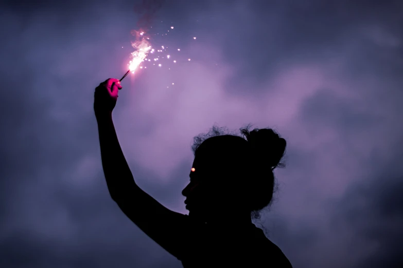 a woman is holding a sparkler in her right hand