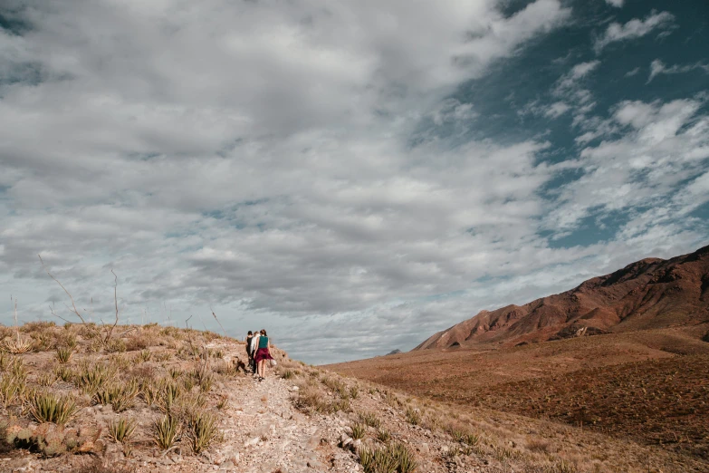 two people are walking down a path in the desert