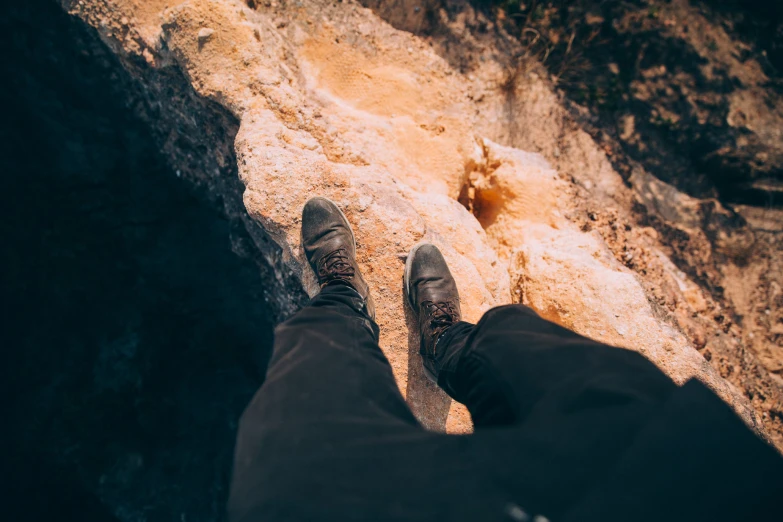 a persons feet and ankles standing on a cliff