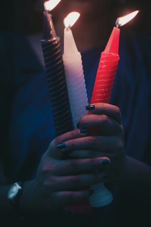 person holding two red candles and lighters