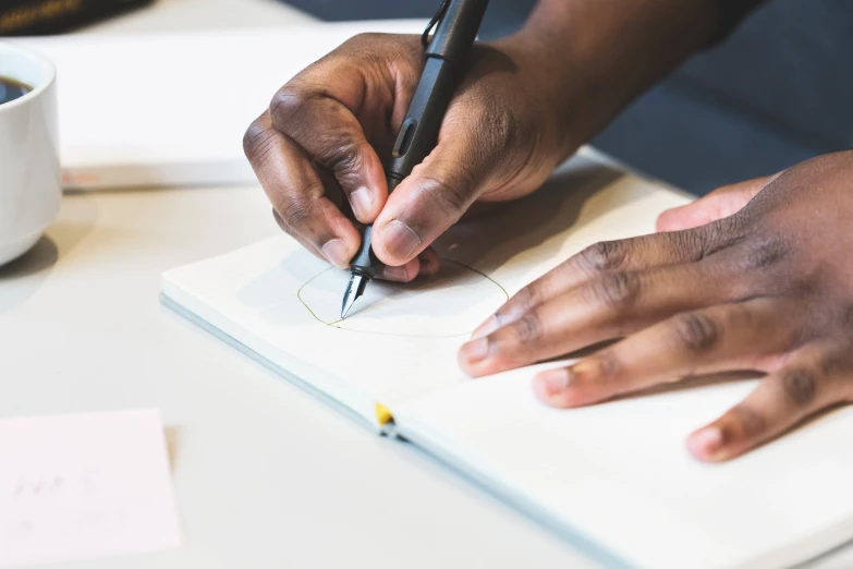 a person sitting at a desk writing on a notebook