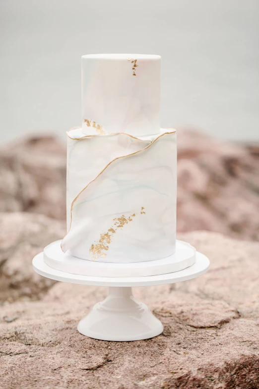 a white marble cake with golden decoration on a stand