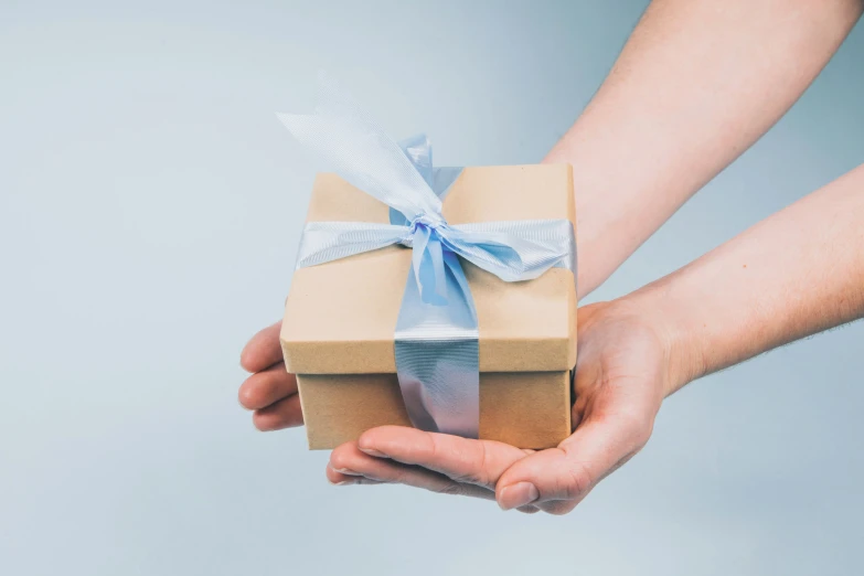 a woman's hand holding a present box with blue ribbon