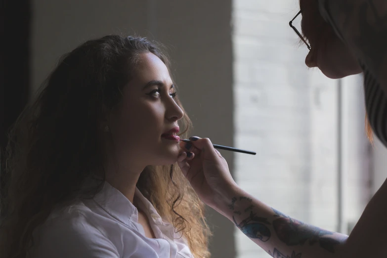 a woman putting lipstick on her face as she brushes her teeth