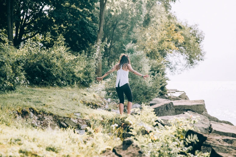 the woman is walking down the mountain by some water