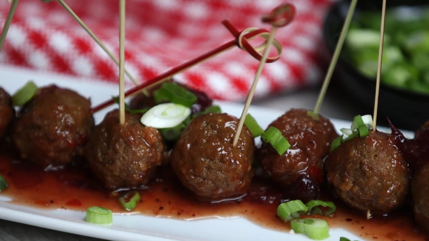 a plate full of meatballs and veggies with sauce and garnishes