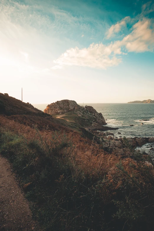 a view of the ocean and island from a grassy hill