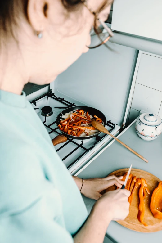 a woman in glasses putting food on the stove