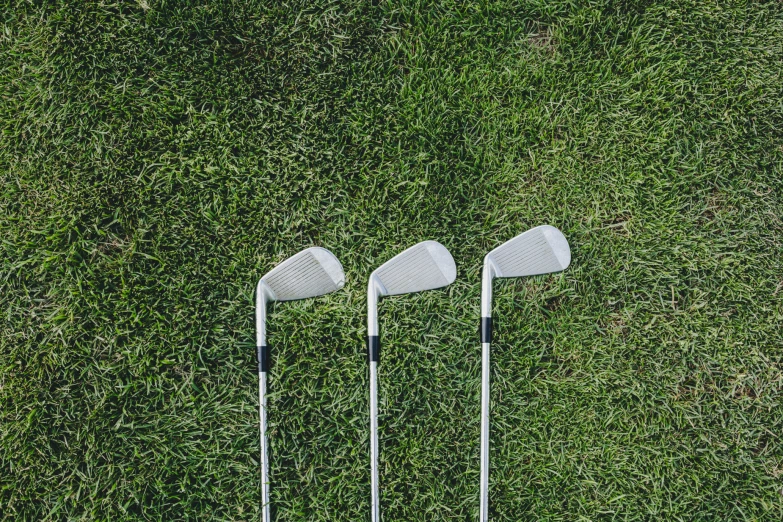 three golf clubs laying next to each other