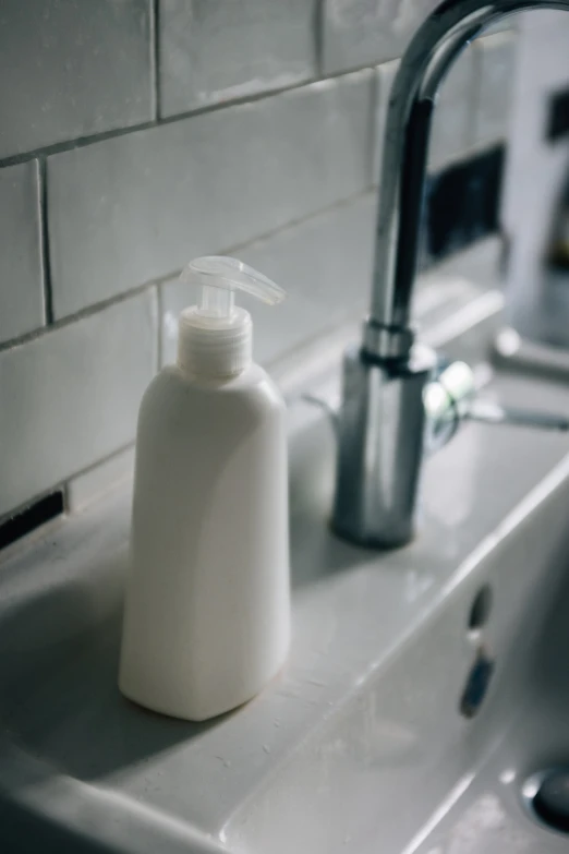 a white bottle of soap sitting on top of a sink