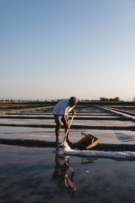 a man kneeling down near a wooden structure in a wet pool of water