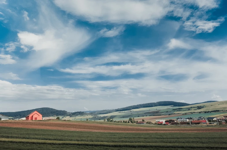 an empty field with a red barn in the distance