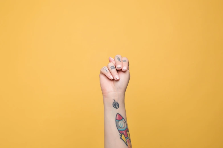 there is a hand holding a tattoo with a rocket