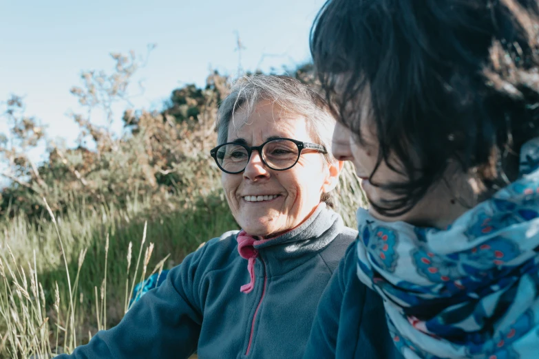 a woman in a blue shirt has her hair parted back and wears glasses