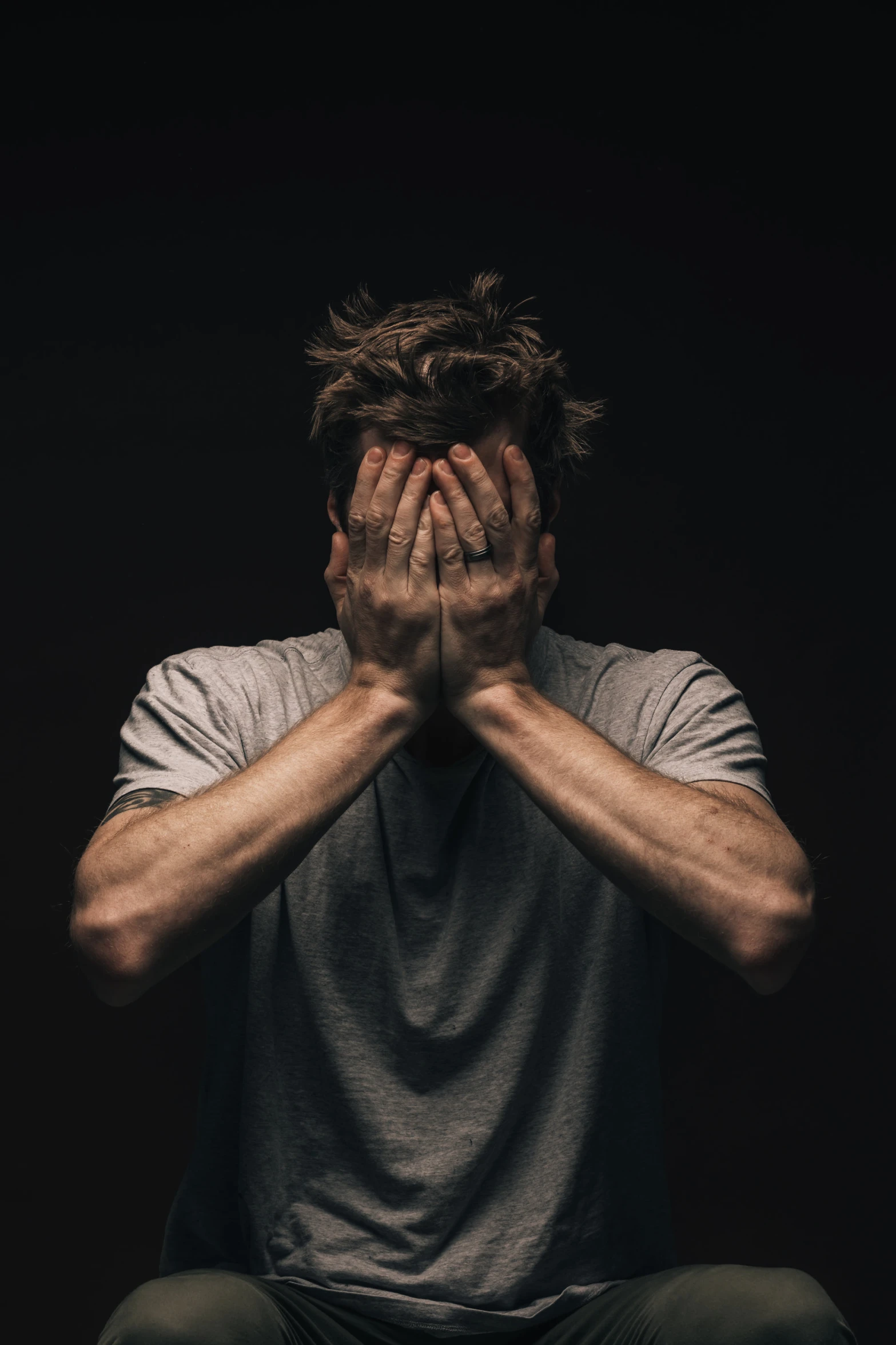 man covering his face with hands sitting down