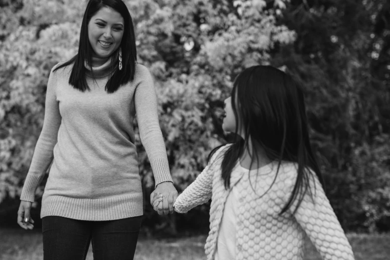 two girls walking hand in hand through an orchard