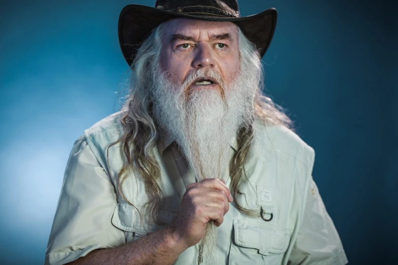 a man with long white hair and a long beard holding a metal object