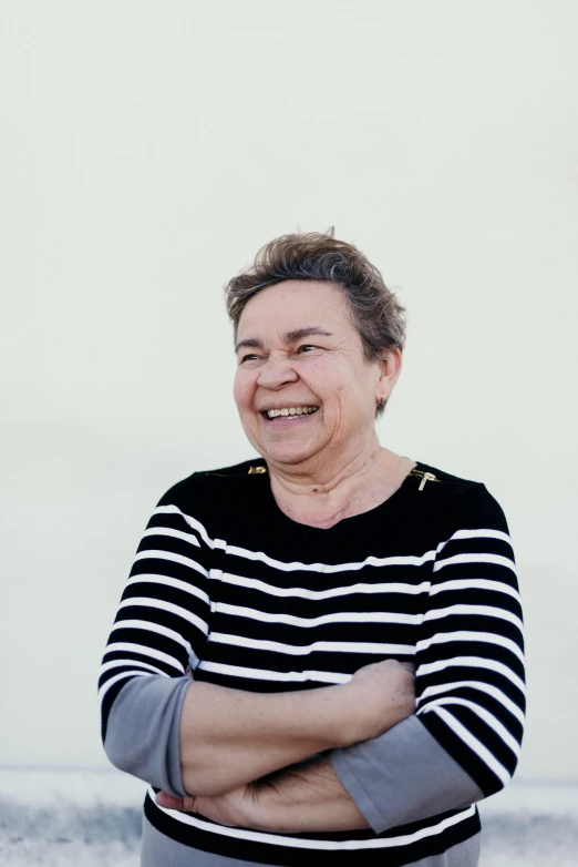 a woman is standing in front of a wall with her arms crossed