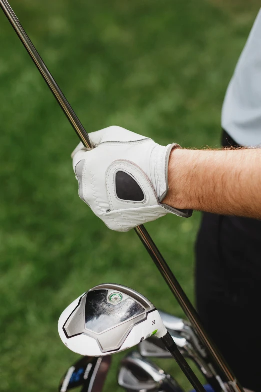 man's hand holding golf club with white glove on it