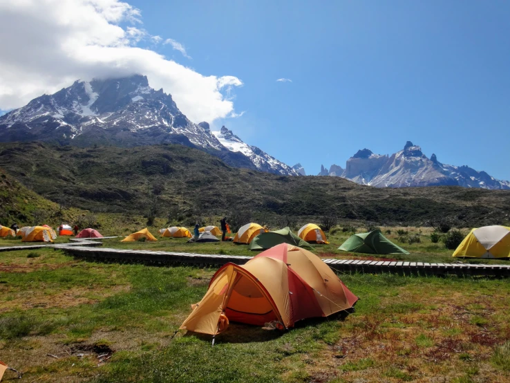 a bunch of tents are lined up in front of a mountain