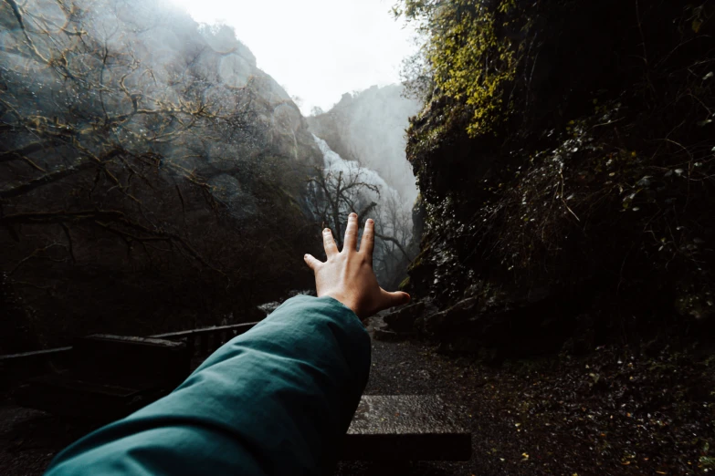 someone pointing at a waterfall in the middle of nowhere