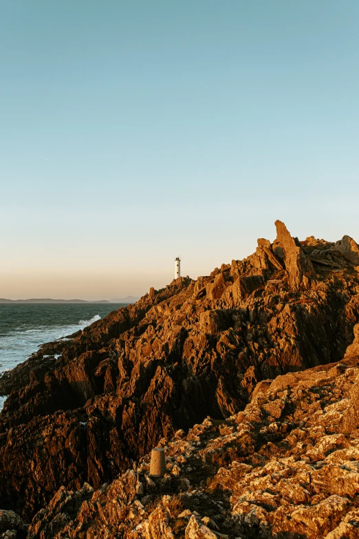 man walking across rocks by water and beach