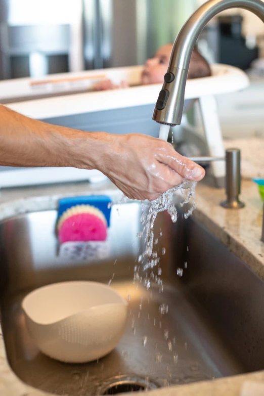 a person washing their hands with a faucet over them