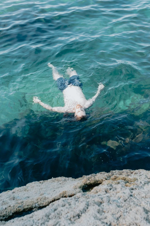 a man floating in water next to rocks