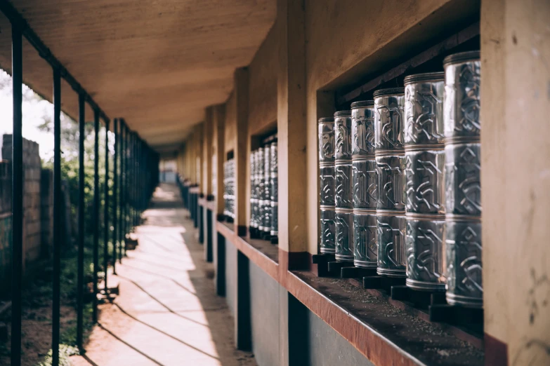 a row of beer cans sitting next to a metal fence