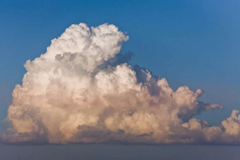 a large, white cloud hangs high in the sky above water