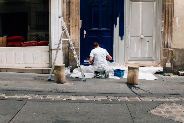 a man painting a door on the side of a building