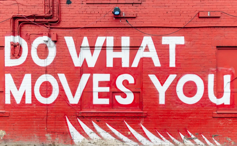 graffiti on a red wall reads do what moves you