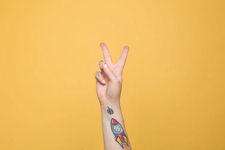 a person with tattoos doing the peace sign