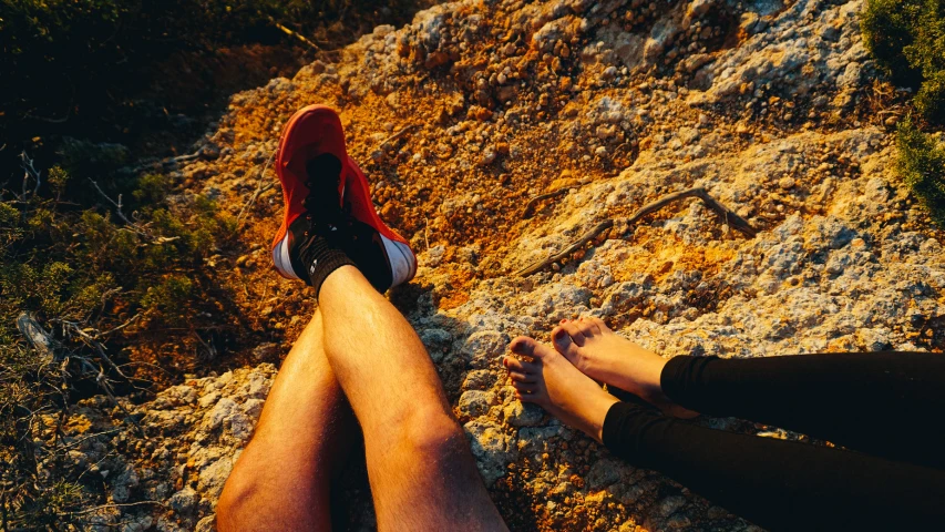 two people sitting on the top of a rocky slope