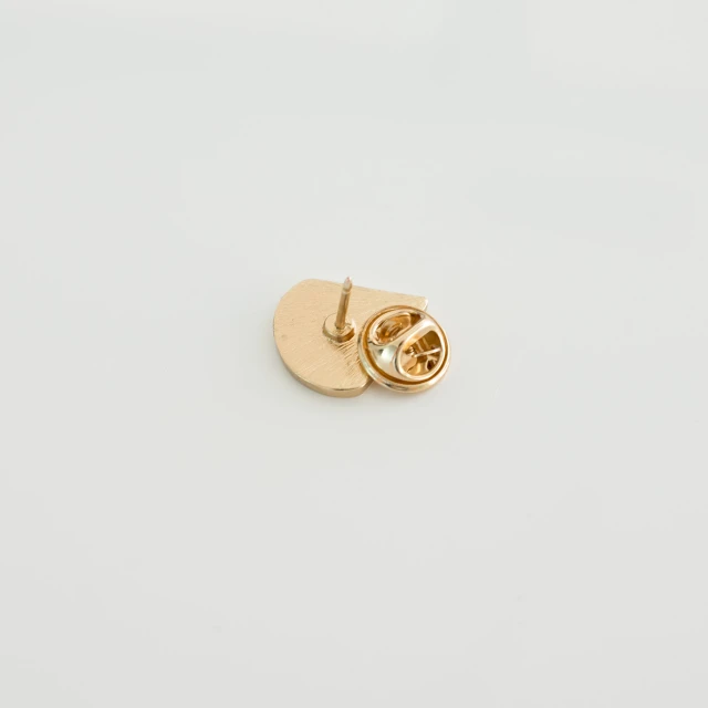 two pairs of gold colored, rounded clippings on a white surface