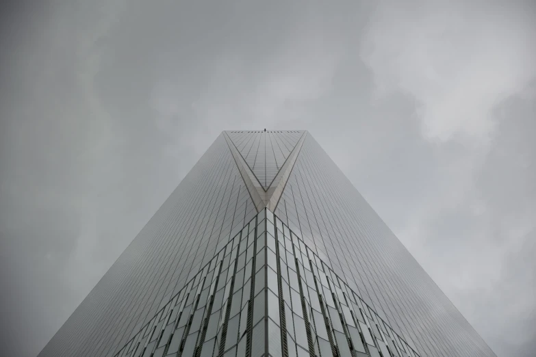 a tall glass and wire structure under a cloudy sky