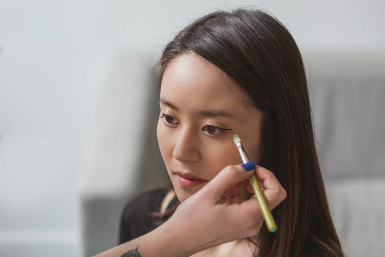 a girl holding a pencil in her right hand and pointing at the same marker